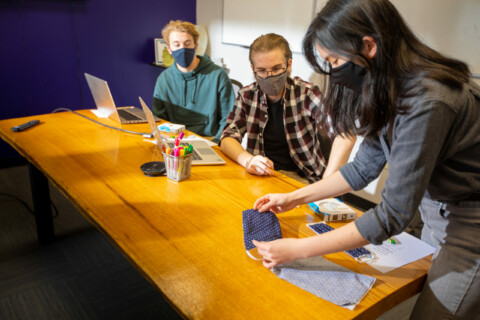Three people talking in a meeting room.